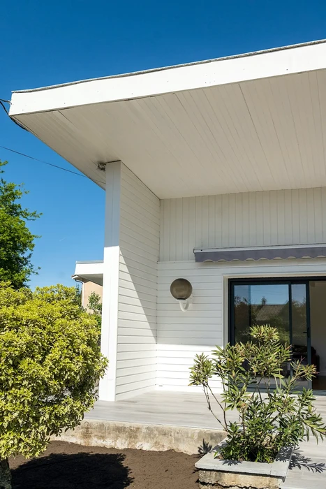 Façade extérieure d'une maison contemporaine avec entrée couverte sous auvent blanc