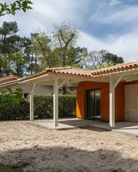 Maison contemporaine avec terrasse couverte et colonnes blanches, toiture en tuiles canal terre cuite, bardage bois vertical à l'entrée