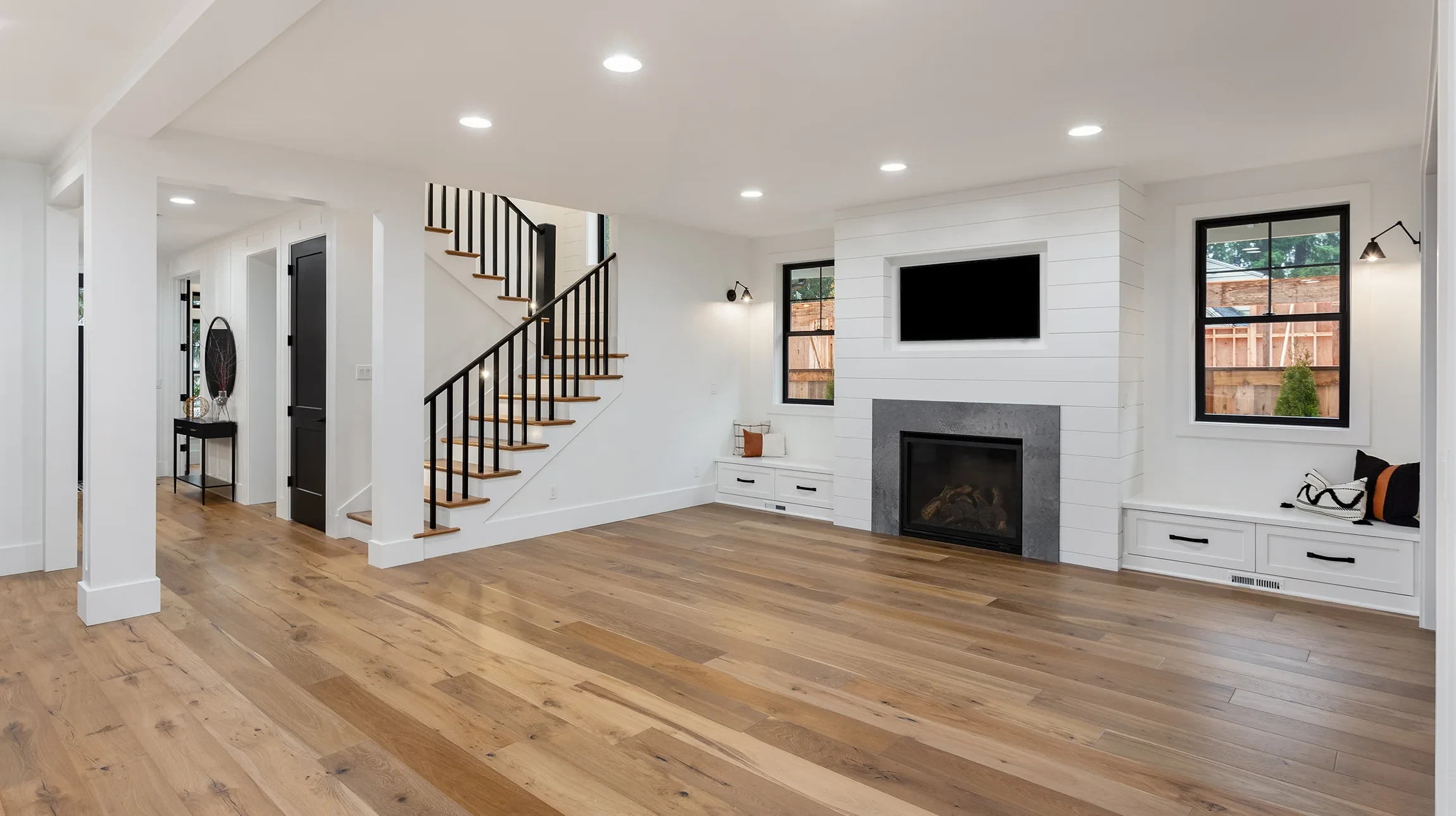 Décor moderne du salon avec canapé en bois marron, oreillers, panier en rotin, vase en verre avec fleurs et accessoires élégants