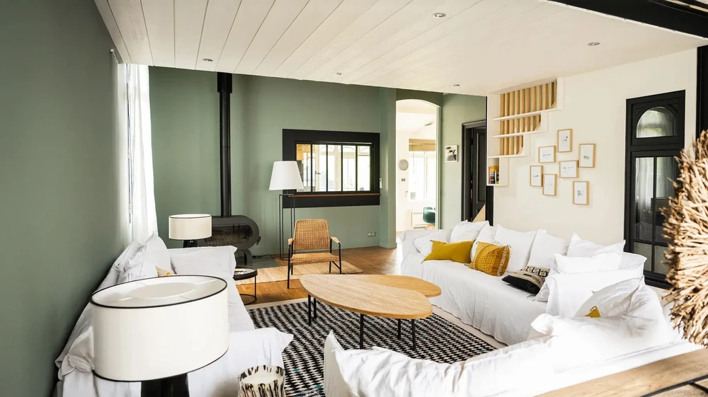 Chambre contemporaine avec papier peint panoramique représentant un paysage pastoral en noir et blanc, lit aux draps bleus, fauteuil design noir et lampadaire arqué